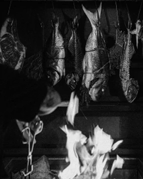 Fish and meat hanging over an open flame in the Óris fire kitchen